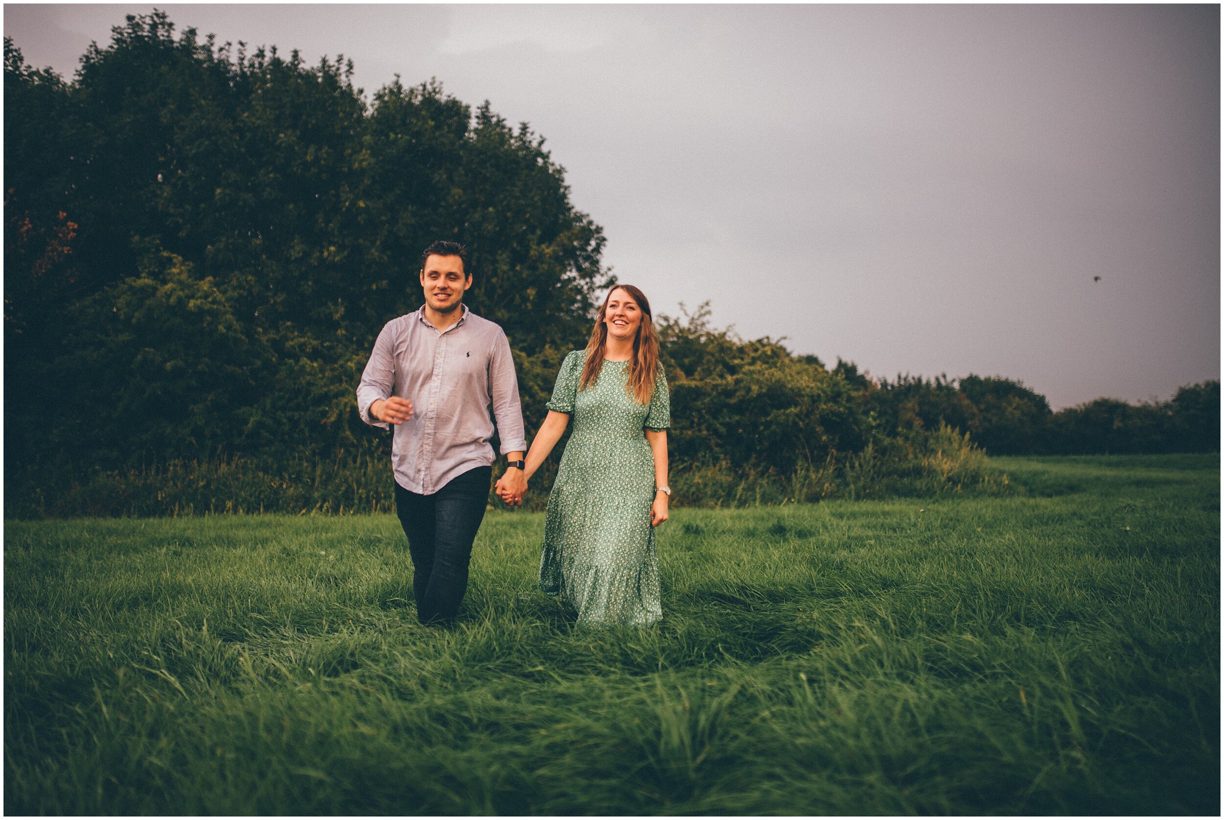 Golden hour as couple walk through Cheshire fields for rainy photoshoot.