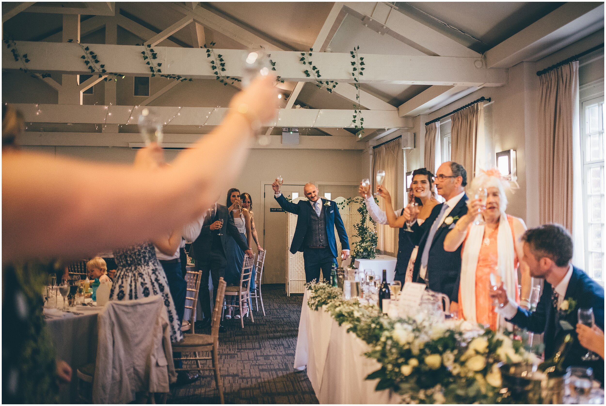 Wedding guests all cheers and toast at Quarry Bank Mill wedding in Cheshire near to Manchester.
