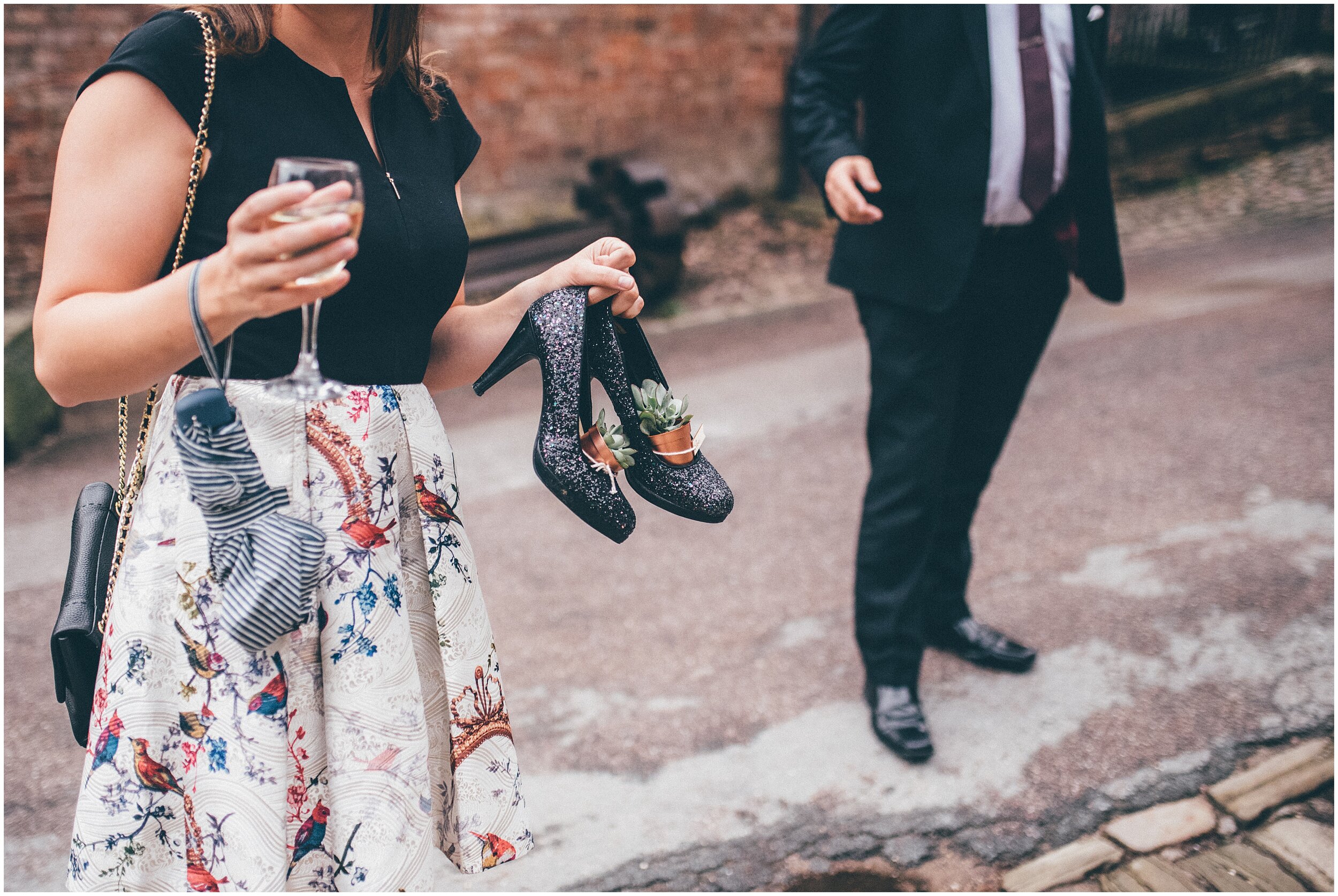 Wedding guests walks around with her shoes off New husband and wife at Quarry Bank Mill wedding in Cheshire near to Manchester.
