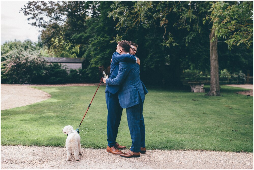Groom and groomsman had a hug whist the dog stands and its.