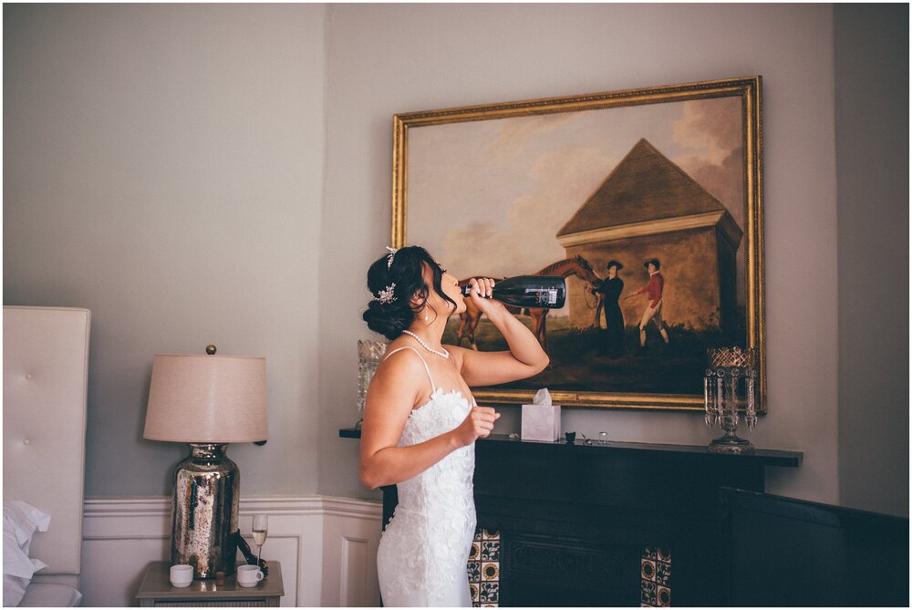 Bride necks a bottle of champagne before her wedding.