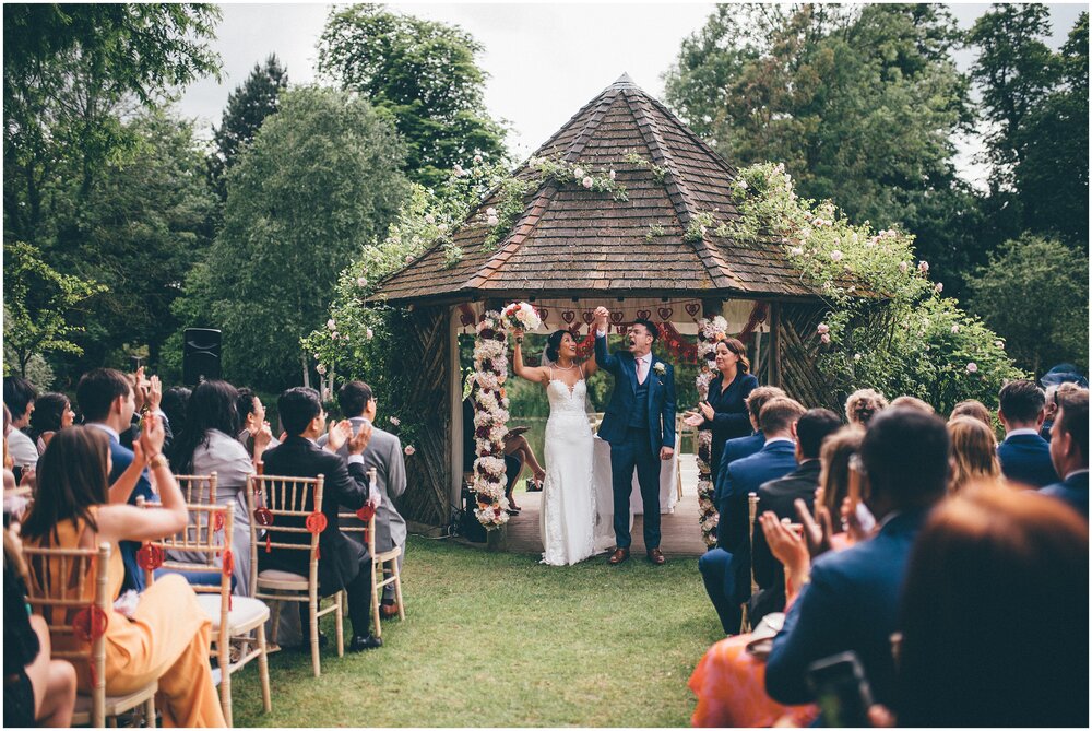 Bride and groom cheer and celebrate being new husband and wife after their outdoor Chinese themed wedding.