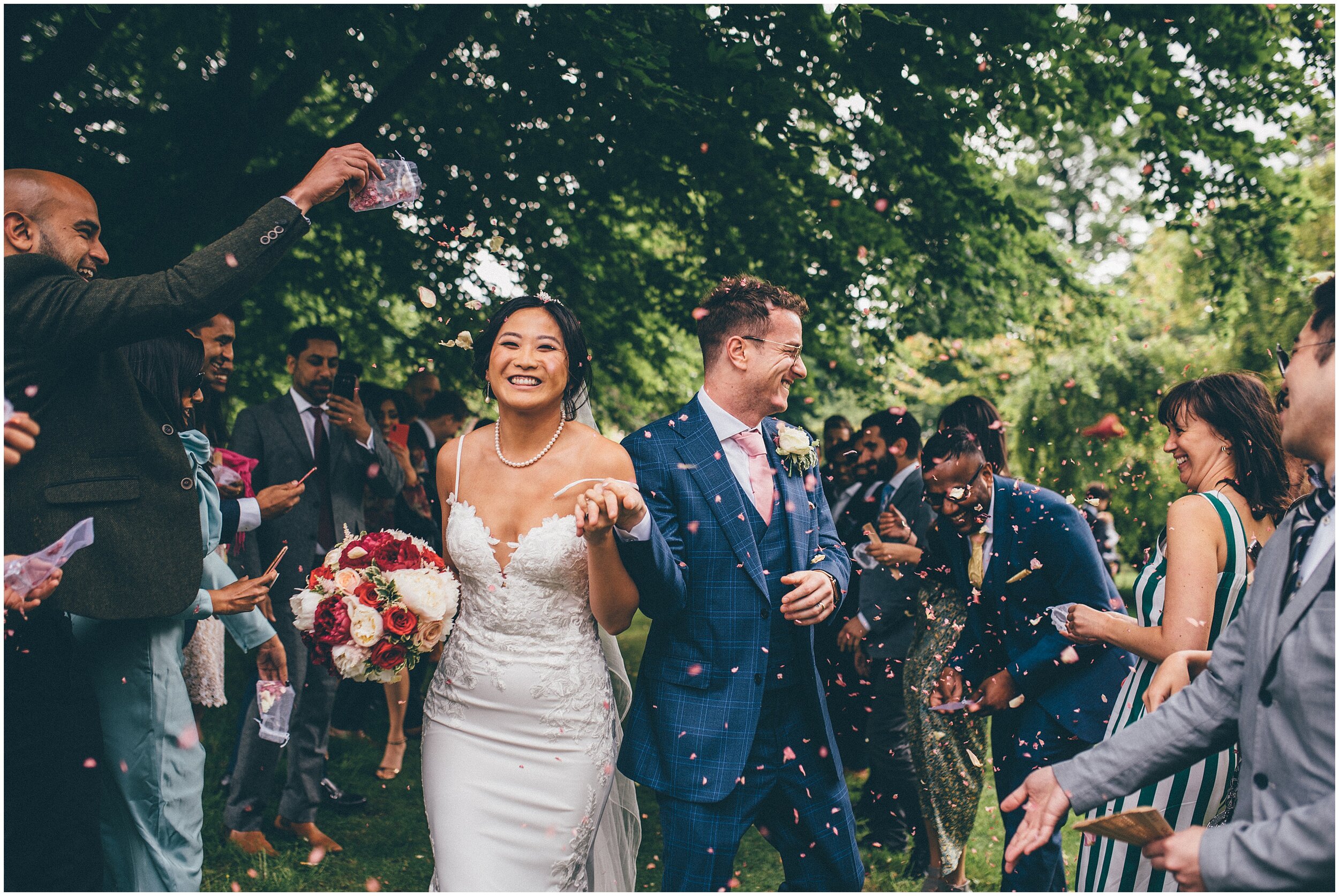 Bride and groom laugh as they have confetti thrown at them.