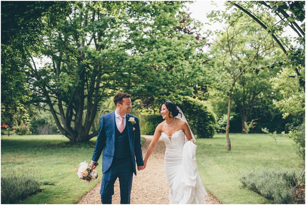 Bride and groom stroll through the grounds of Chippenham Park gardens.