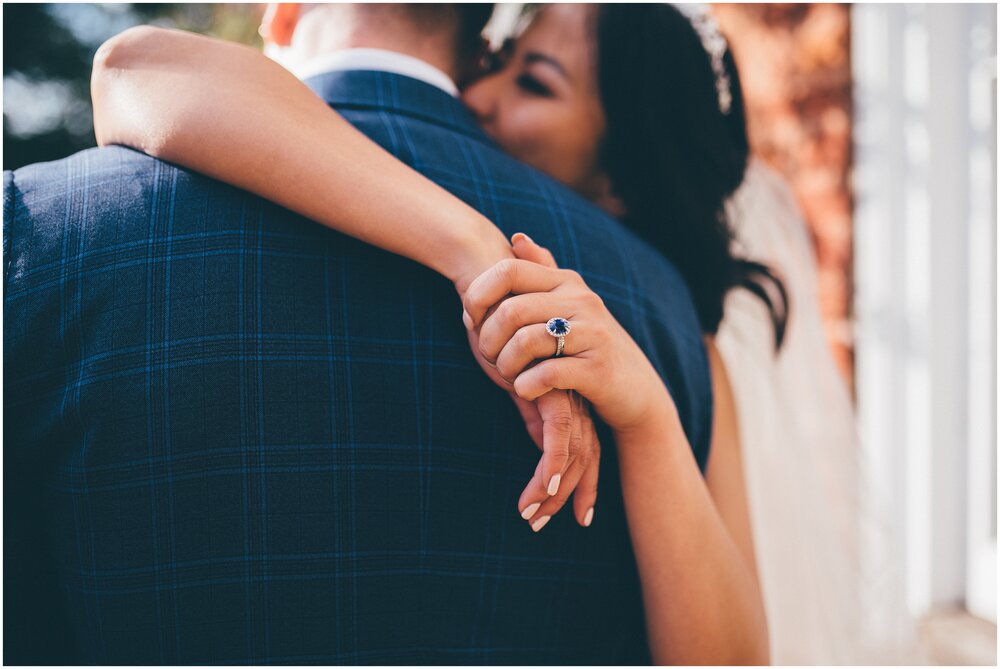 Bride hugs her husband, with. beautiful angle of her sapphire engagement ring. 