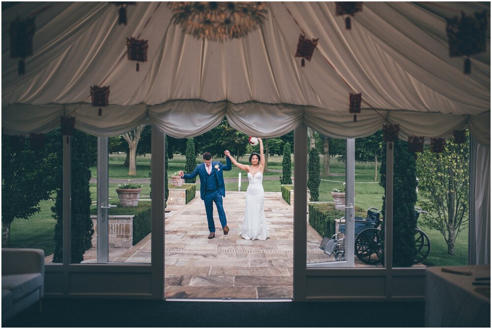 Bride and groom wave their arms in the air and celebrate with their guests.