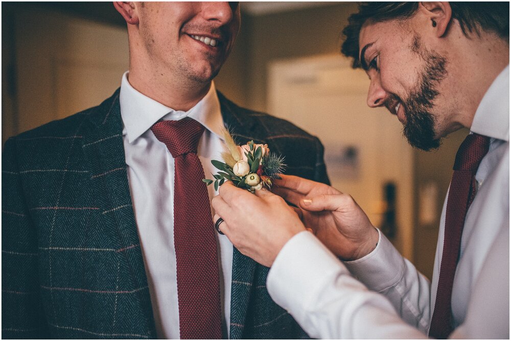 Best Man fastens grooms buttonhole on before the destination wedding.
