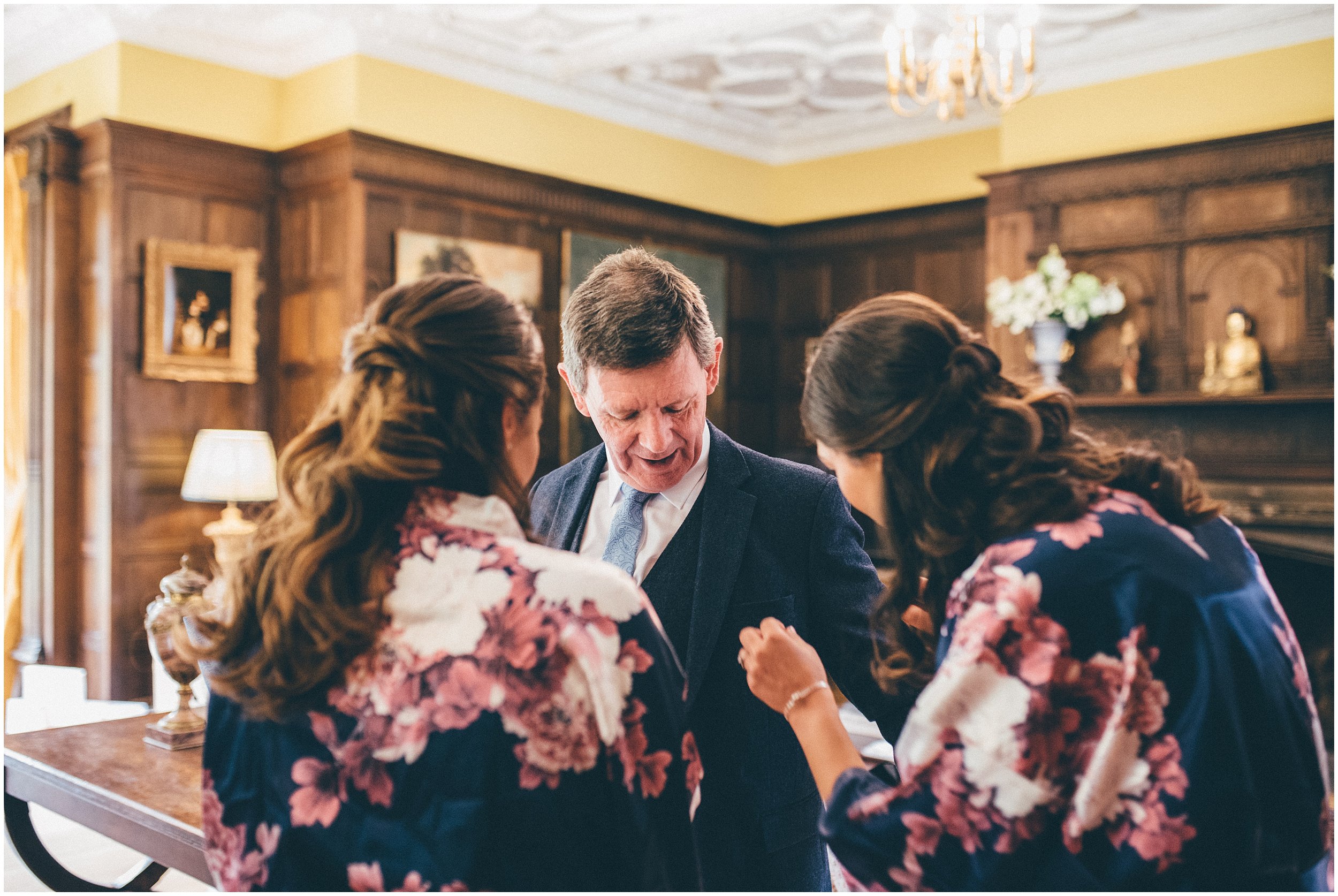 Bridesmaids help brides dad get ready on the wedding morning.