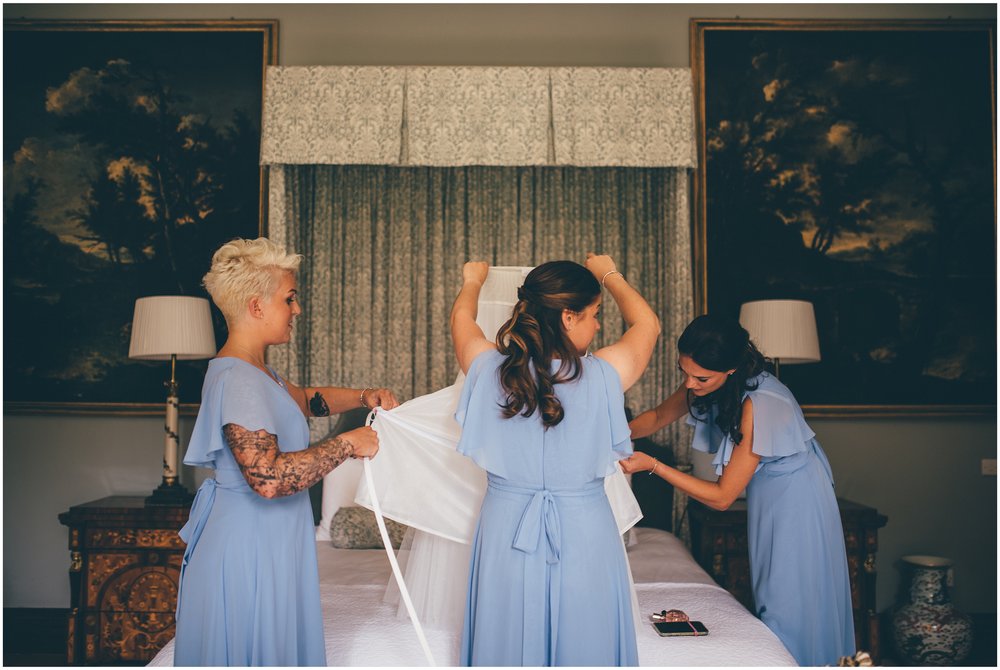 Bridesmaids hold Essence of Australia gown before the bride puts it on.