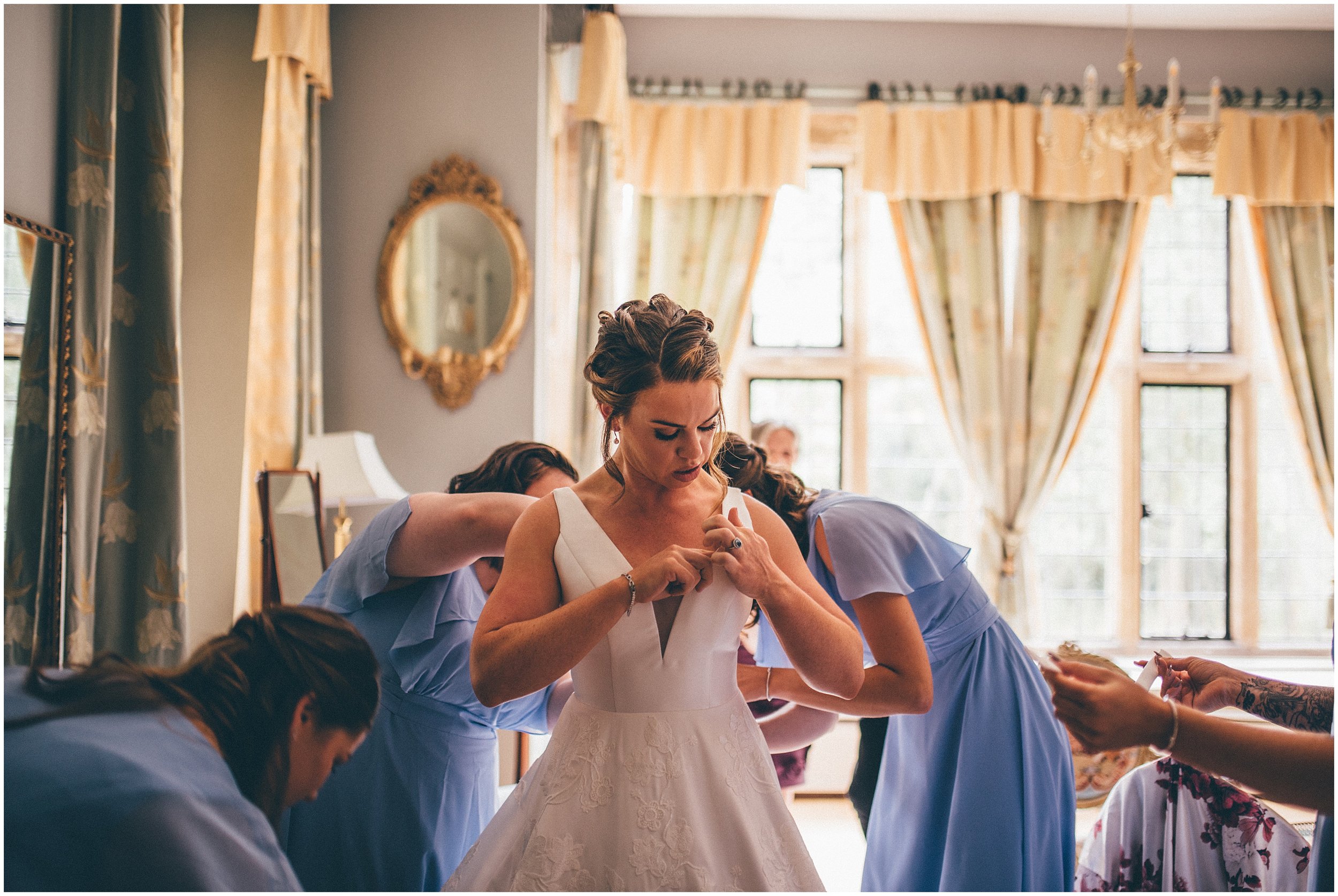 Bridesmaids help the bride get dressed.