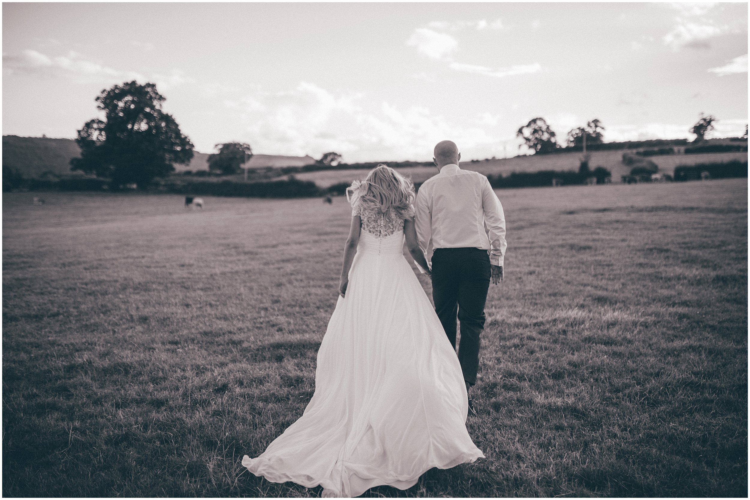 Bride and Groom walk through fields at Tower Hill Barns in North Wales