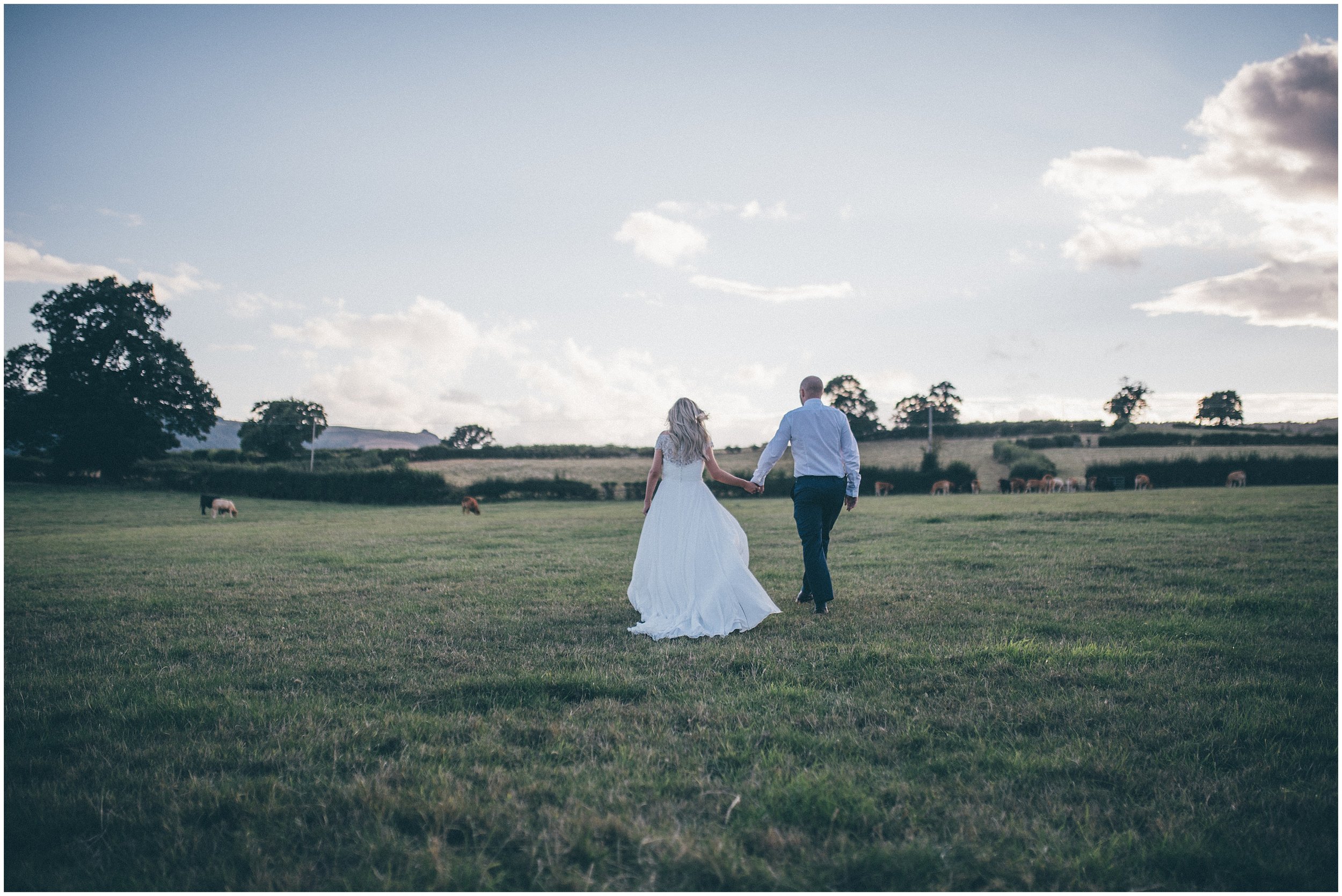 Bride and Groom walk through fields at Tower Hill Barns in North Wales