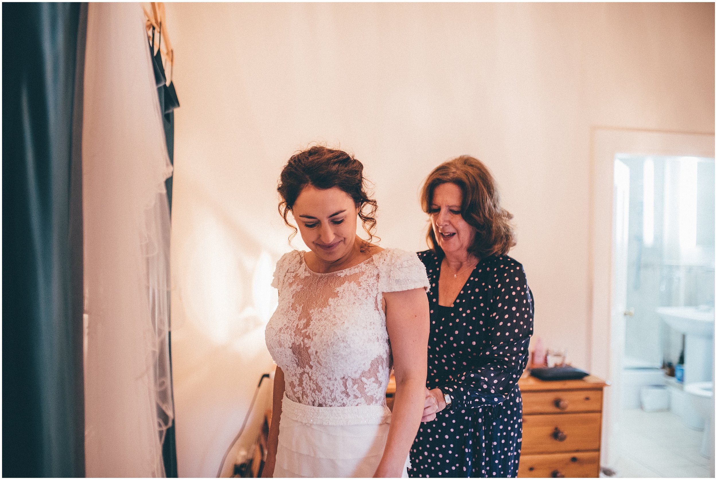 Bride's mum helps her daughter into her wedding dress