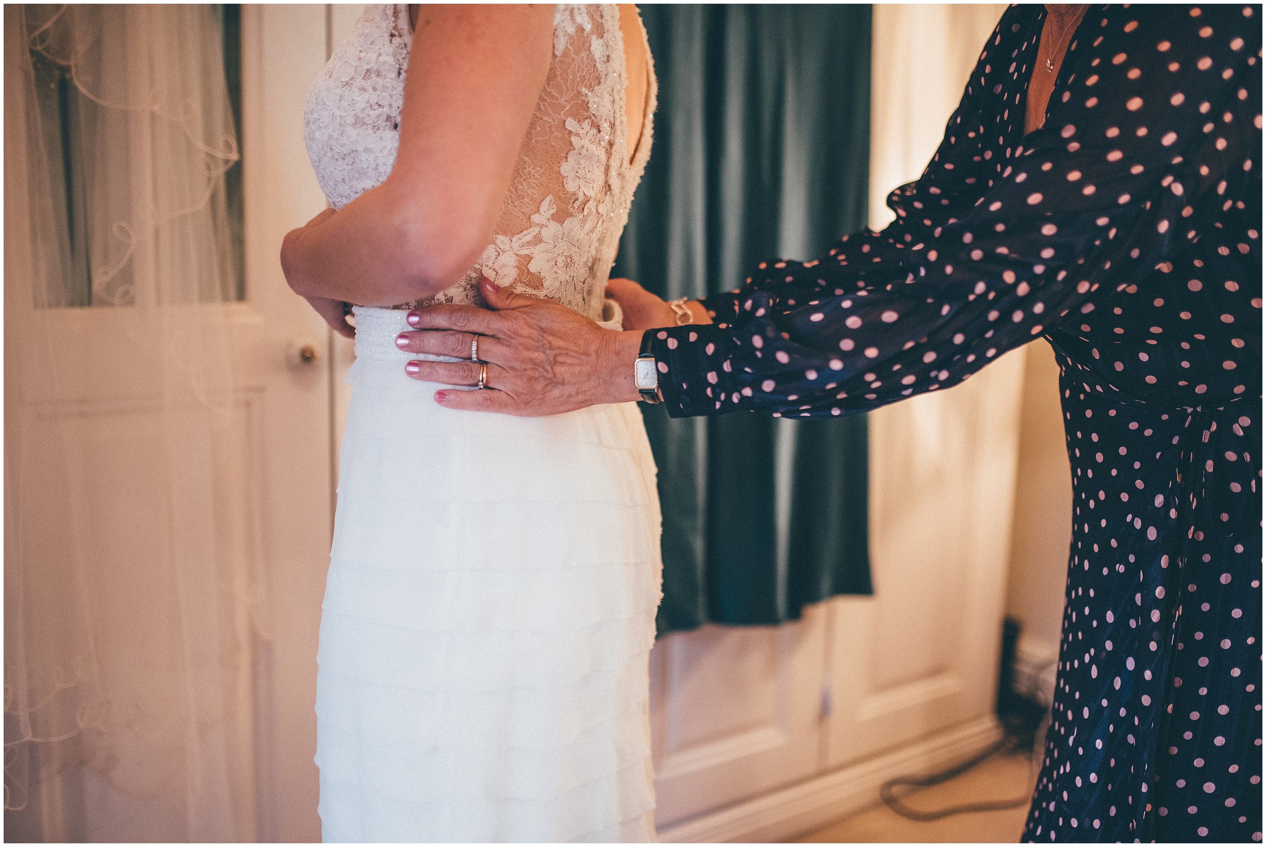 Bride's mum helps her daughter into her wedding dress