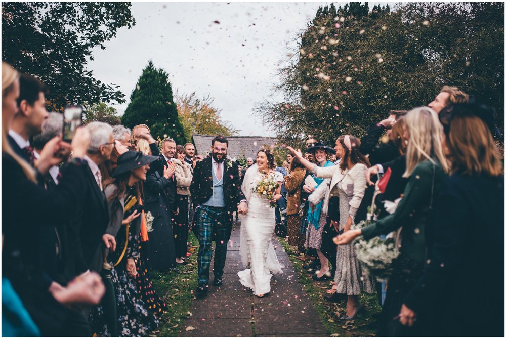 Bride and groom walk through a tunnel of confetti at their Cheshire wedding