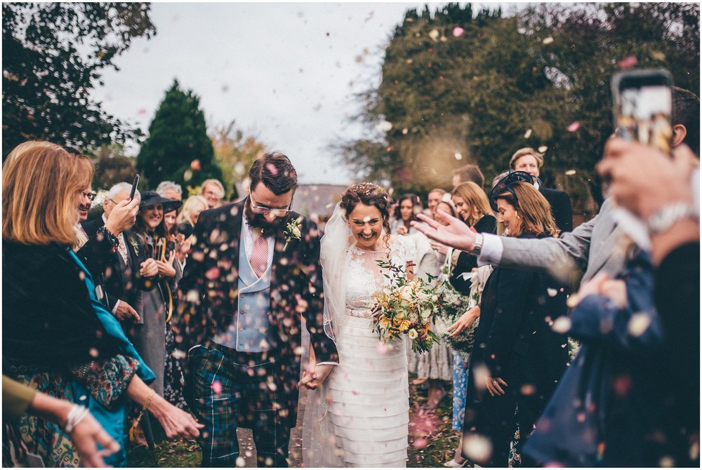 Bride and groom walk through a tunnel of confetti at their Cheshire wedding