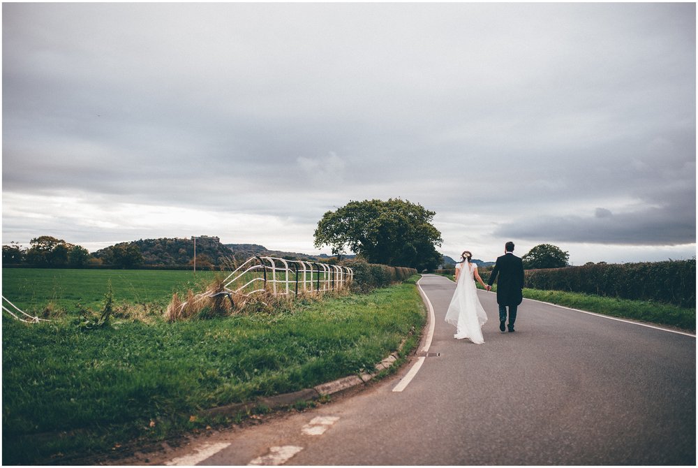 Bride and Groom pose for their wedding photographs in Cheshire with Beeston Castle behind them