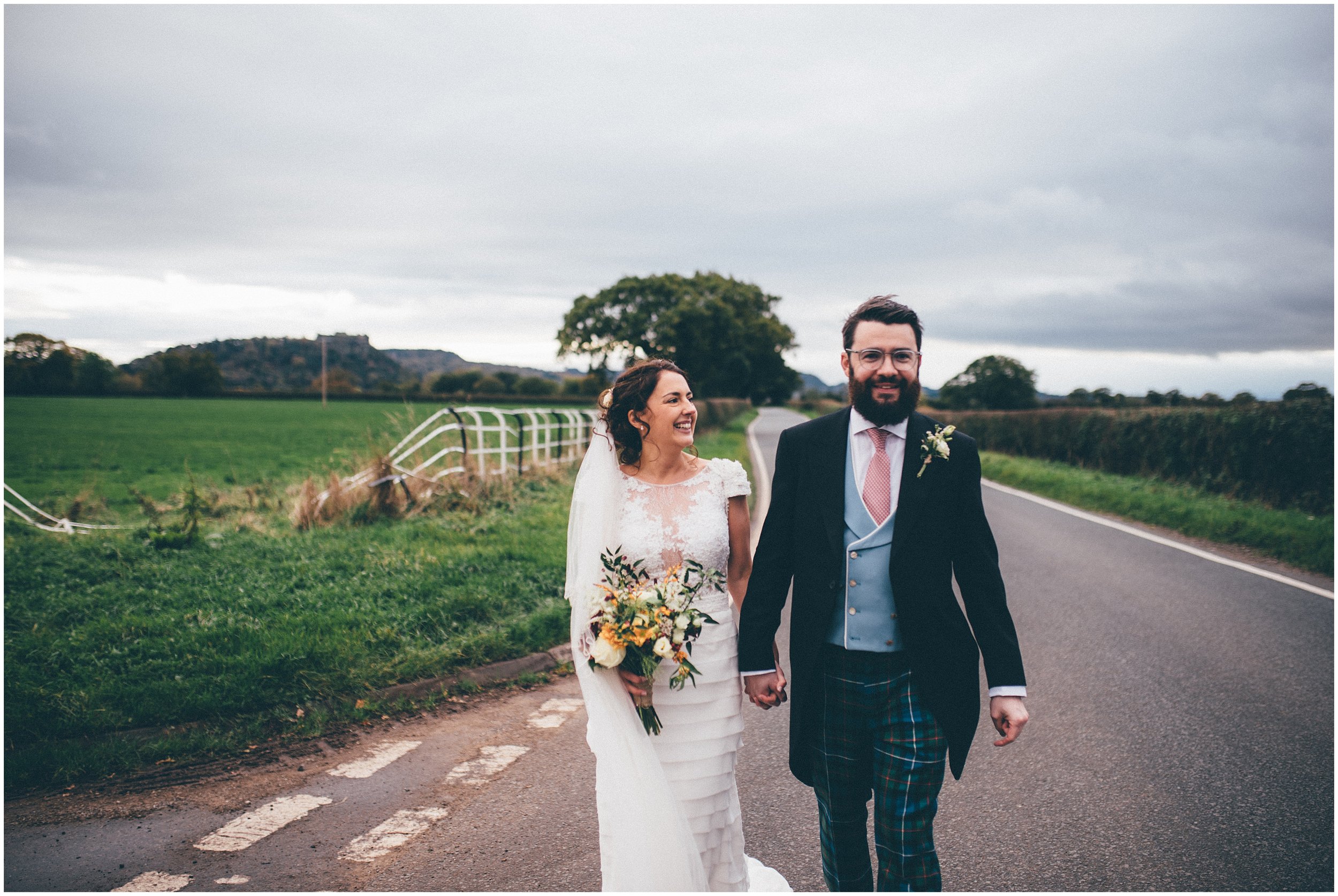 Bride and Groom pose for their wedding photographs in Cheshire with Beeston Castle behind them