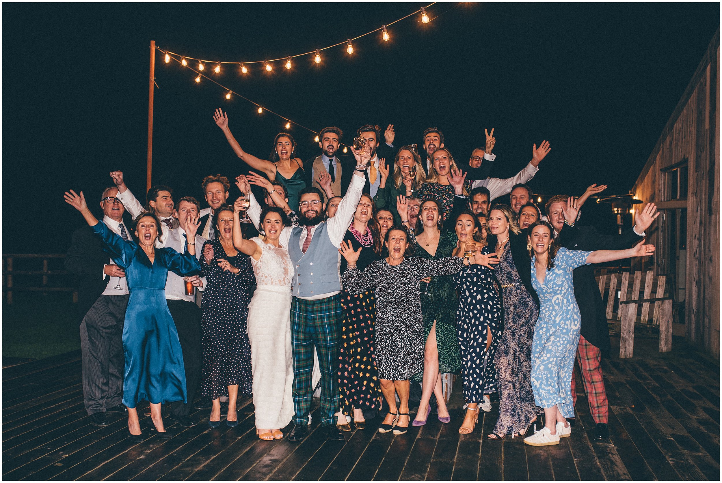 Wedding guests cheer on the bride and groom outside at Grange Barn in Cheshire