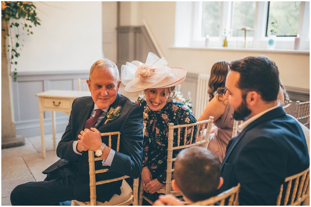 Bride's mum and dad look at cute ring bearer during ceremony