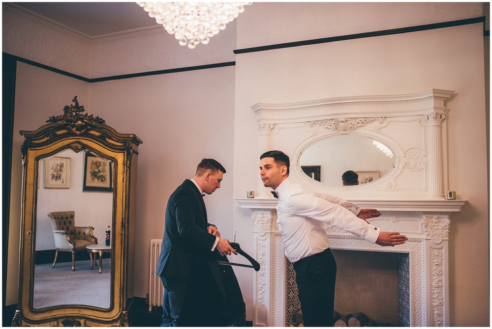 Grooms puts on his suit jacket at his Tyn Dwr Hall wedding 