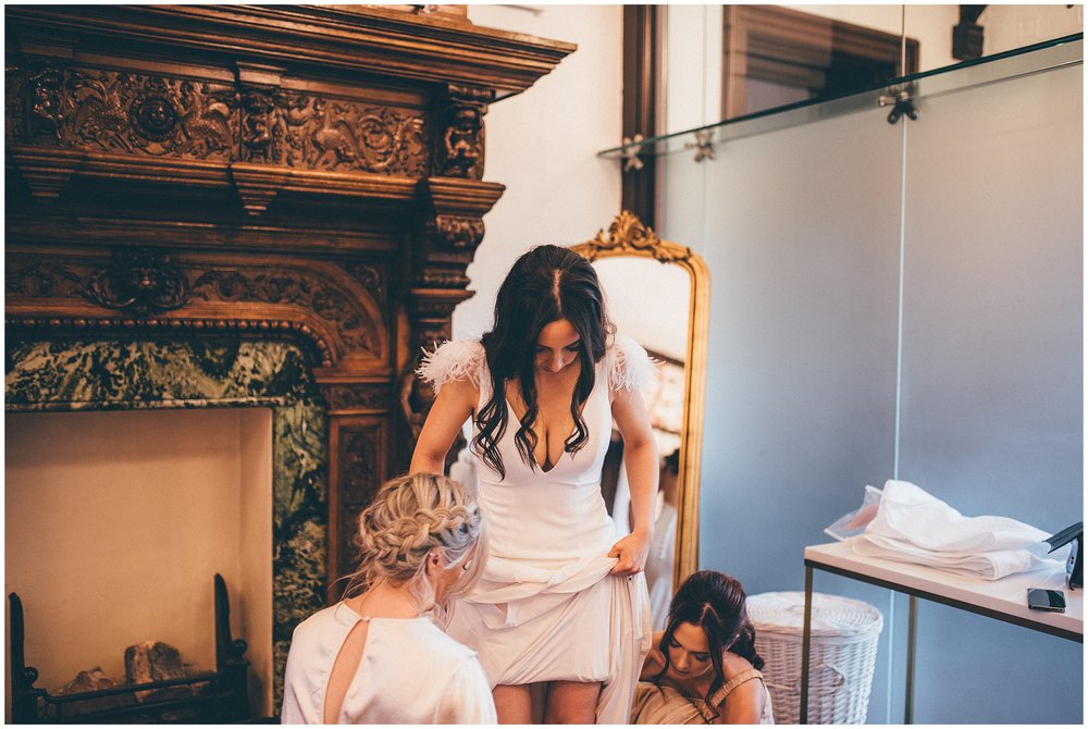 Bridesmaids help bride into her dress at Tyn Dwr Hall in North Wales