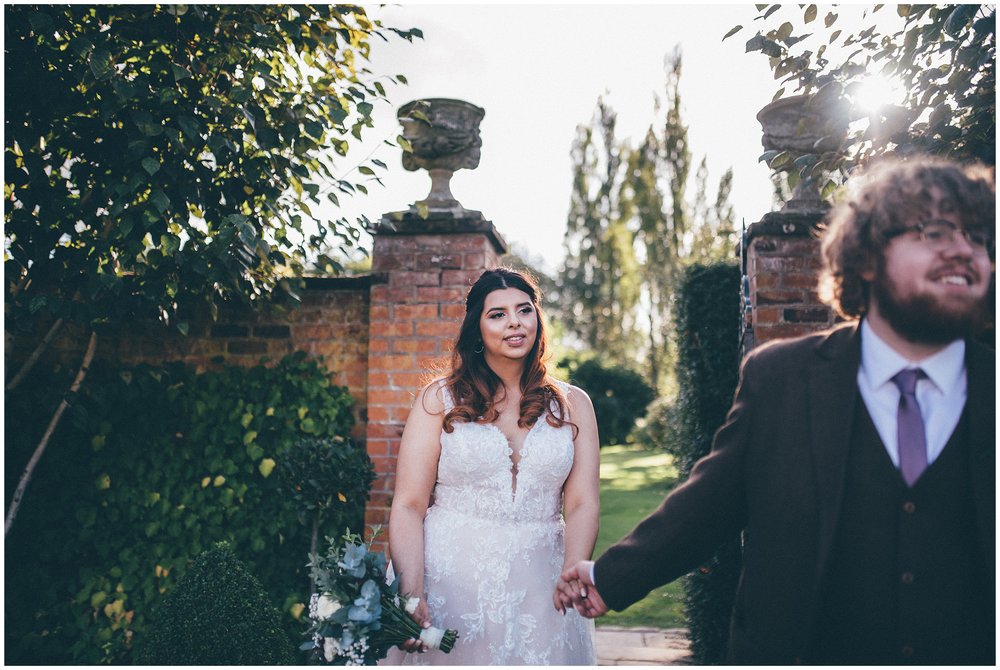 Groom leads bride out of the gardens at Colshaw Hall