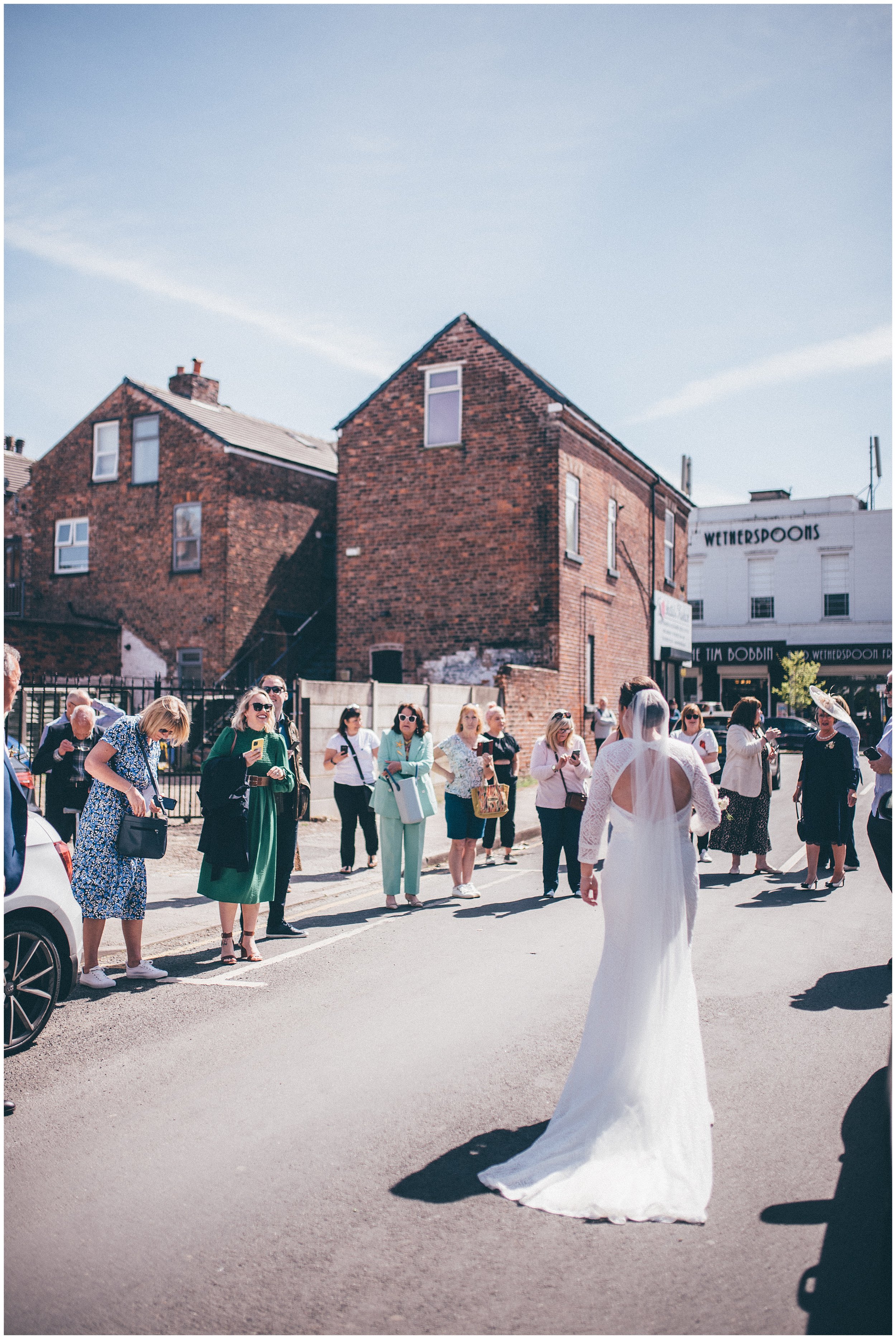 As bride arrives at the church her guests all applaud in Manchester