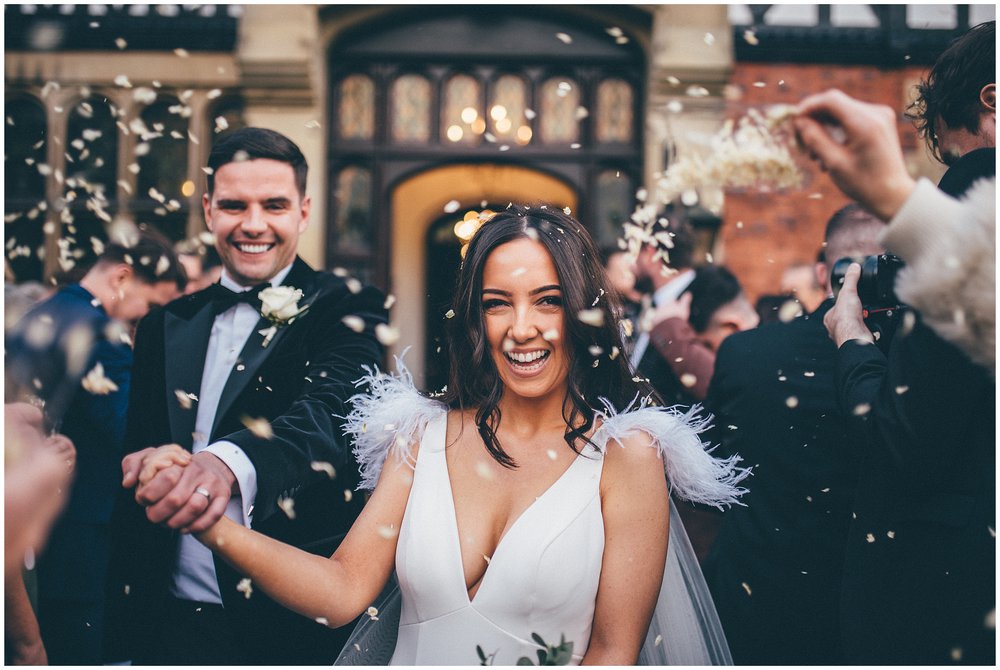 Guests throw confetti at beautiful bride and groom at Tyn Dwr Hall