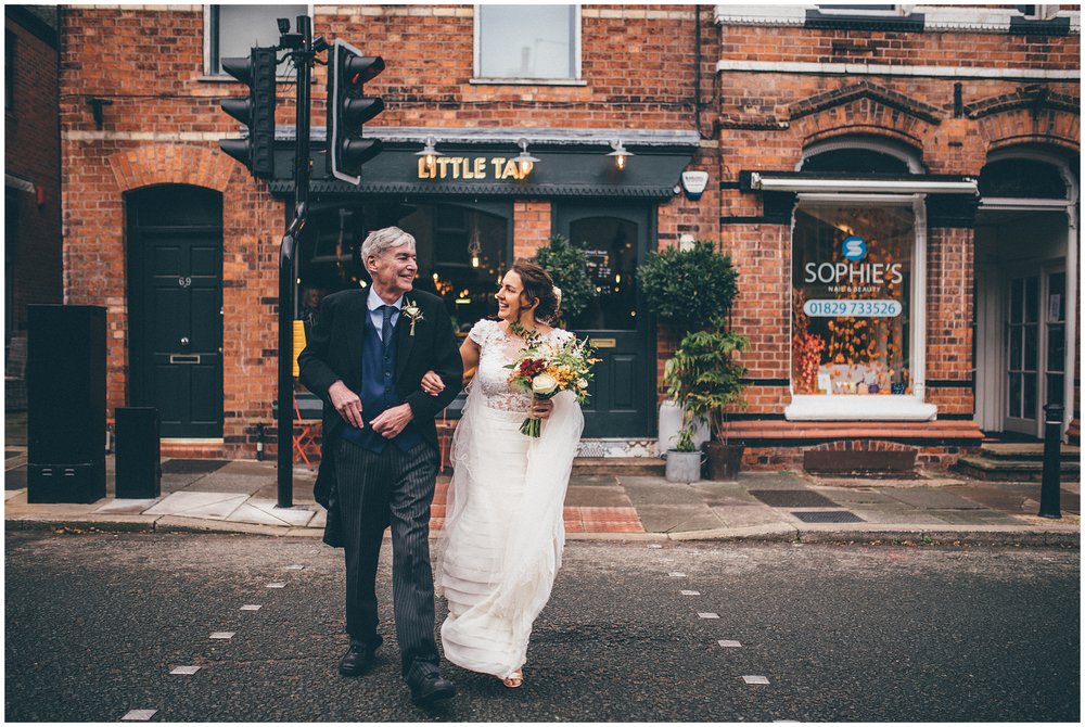 Bride and her dad walk through Tarporley, Cheshire to her wedding