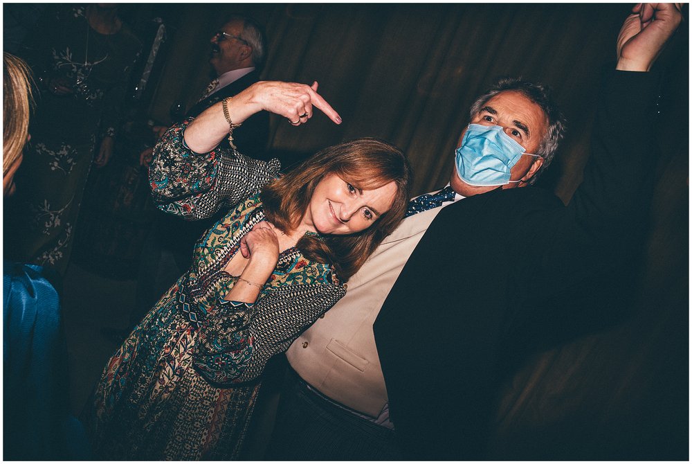 Weddings guests dance at Grange Barn wedding whilst one of them wears a face mask