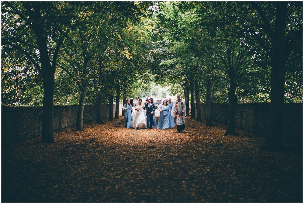 Bridal party walk to church in the sunlight at Suffolk wedding