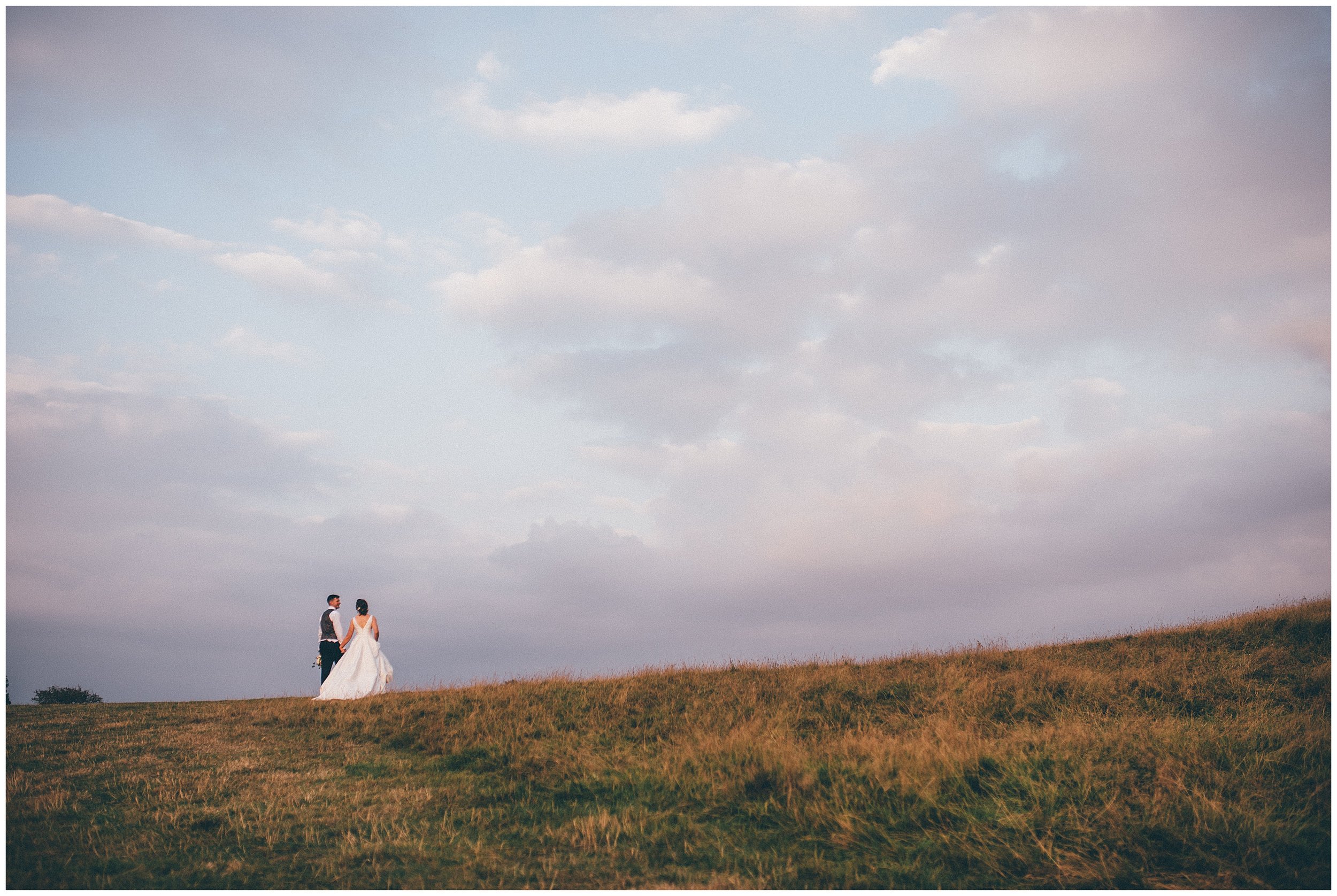 Bride and groom walk up the hill together at their wedding in Suffolk