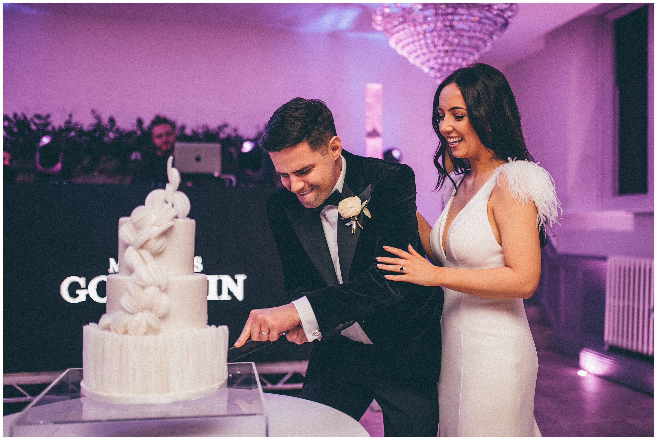 Groom tries really hard to cute the ornate wedding cake at Tyn Dwr Hall