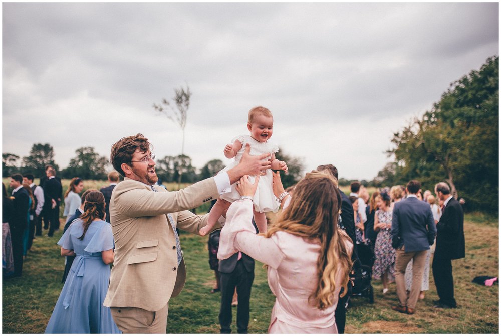 Family throw their little girl in the air at Suffolk garden wedding