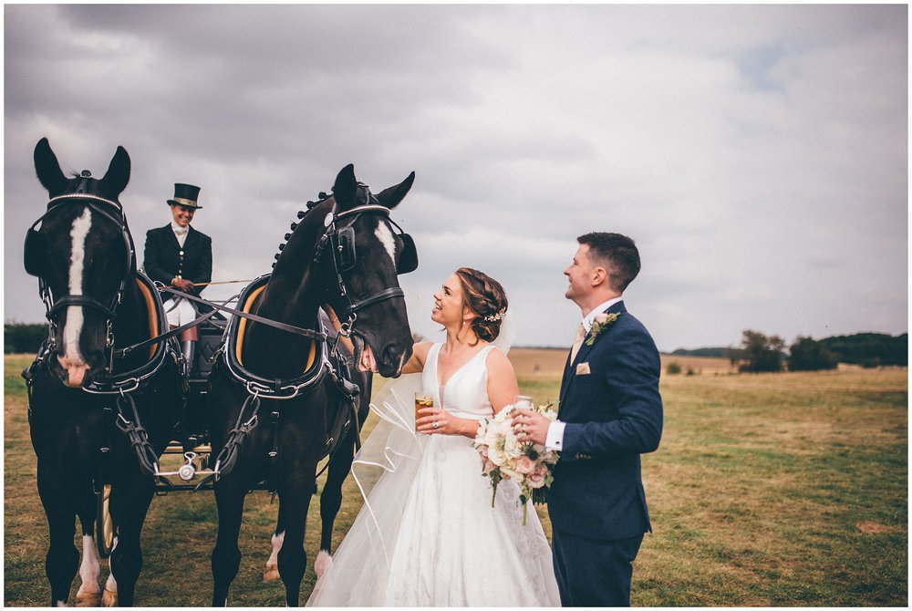 Bride and groom stroke the horse that they travelled on to their wedding
