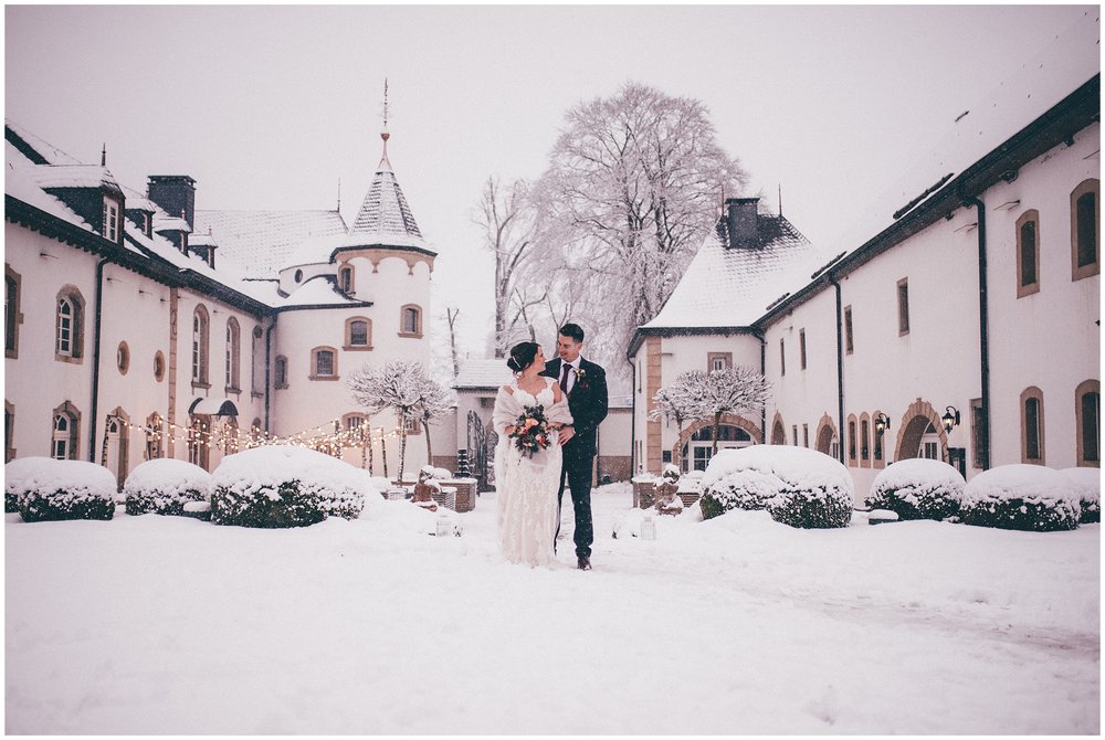 Bride and groom gaze lovingly at each other in the snow at Chateau D'Urspelt in Luxembourg
