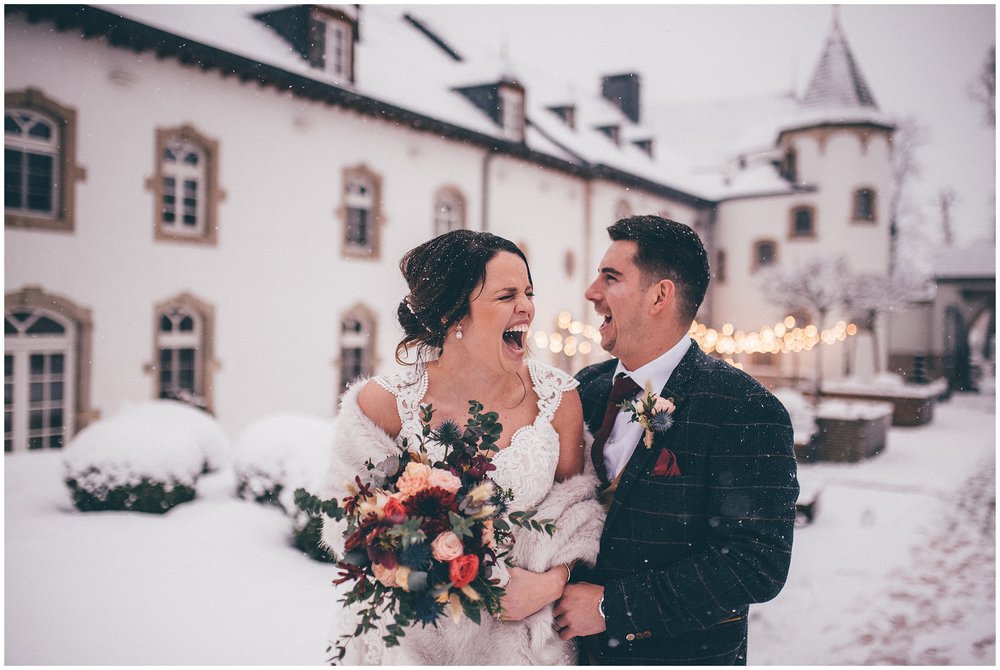 Bride and groom laugh in the snow at their wedding in Luxembourg