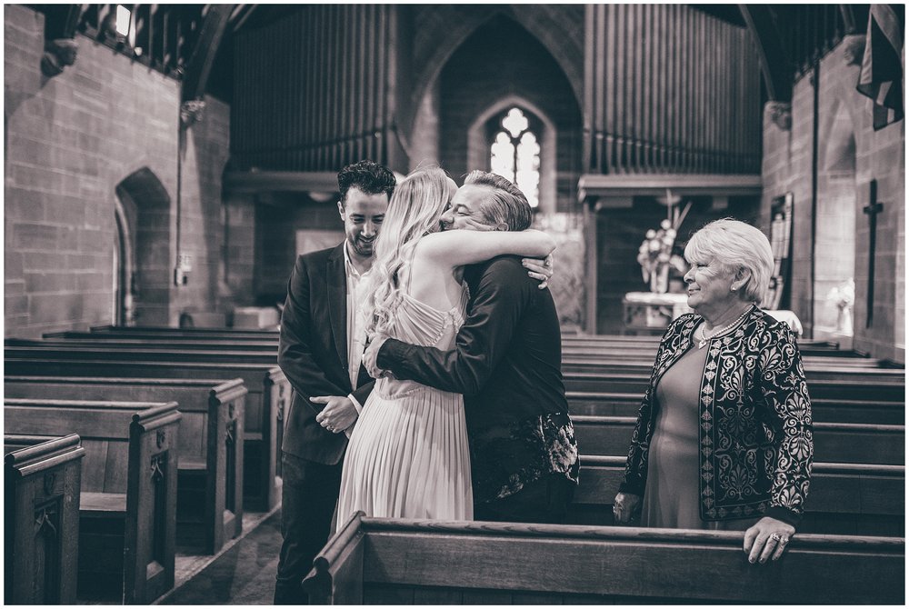 Bride hugs her guests as other guests look on at Chester church