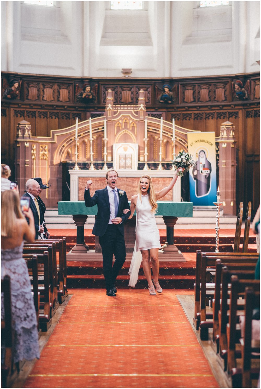 Bride and groom celebrate at the top of the aisle after being announced as husband and wife