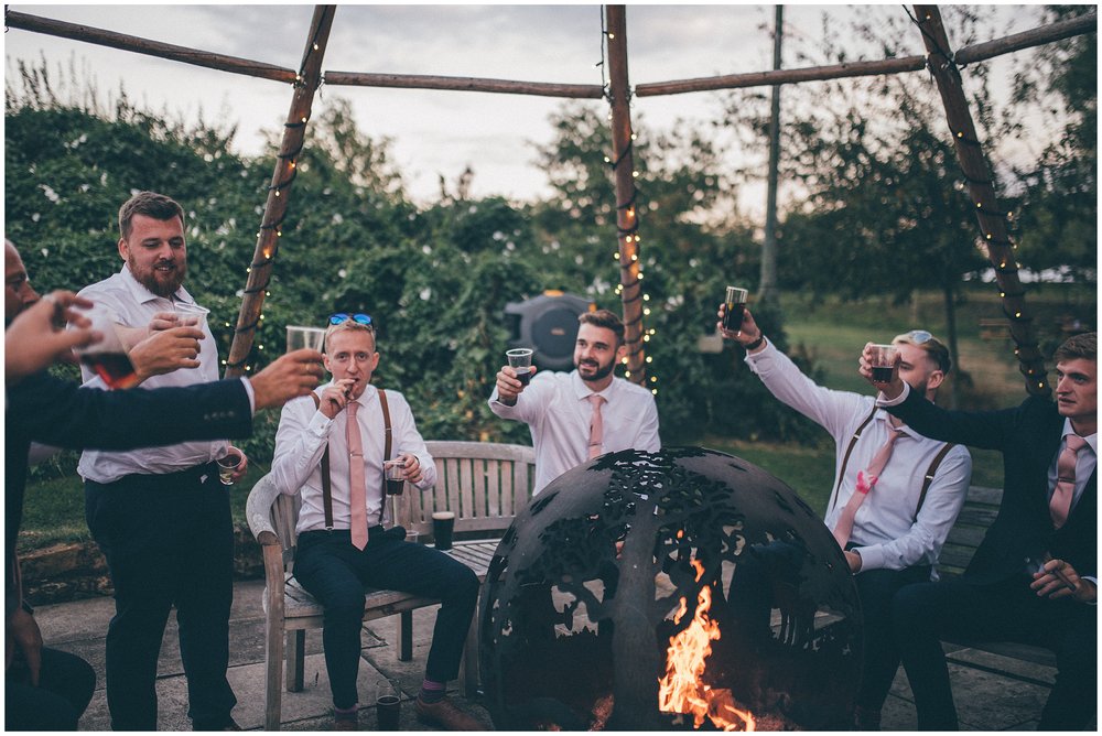Groomsmen all cheers and smoke cigars around the fire pit at Skipbridge Country weddings