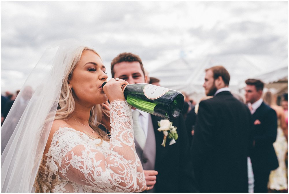 Bride drinking champagne from the bottle at her Cheshire marquee wedding