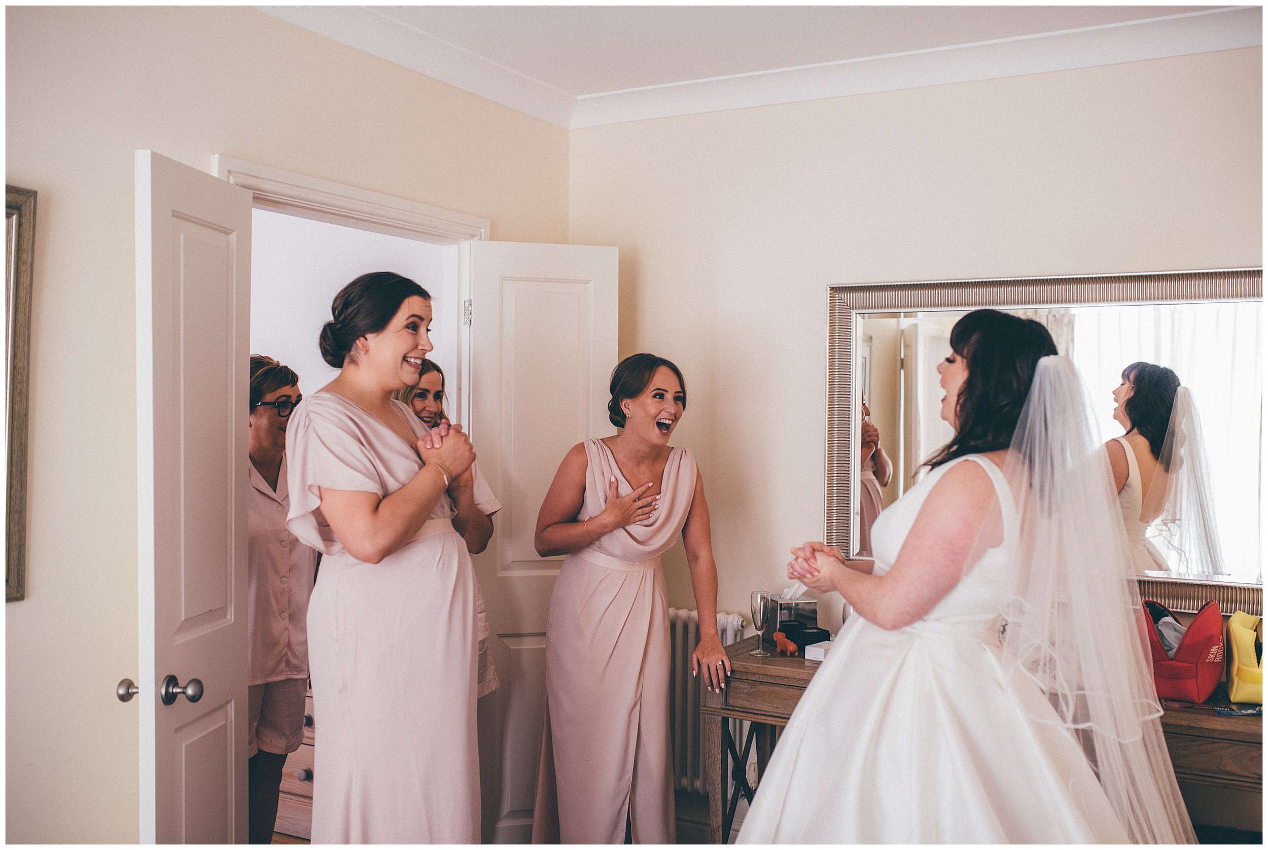 Bridesmaids see the bride in her dress for the first time at Rowton Hall