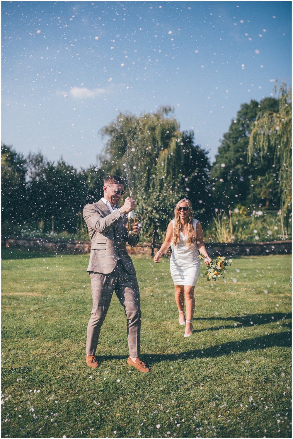 Groom sprays champagne at their garden wedding in Cheshire
