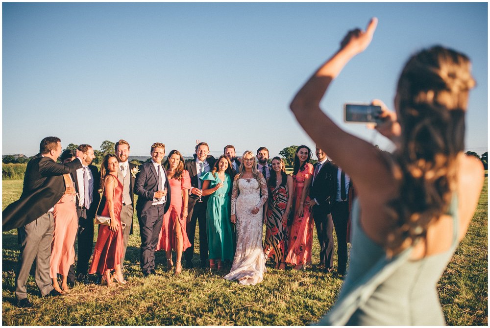 Guest takes photograph of group of guests at marquee wedding in Cheshire