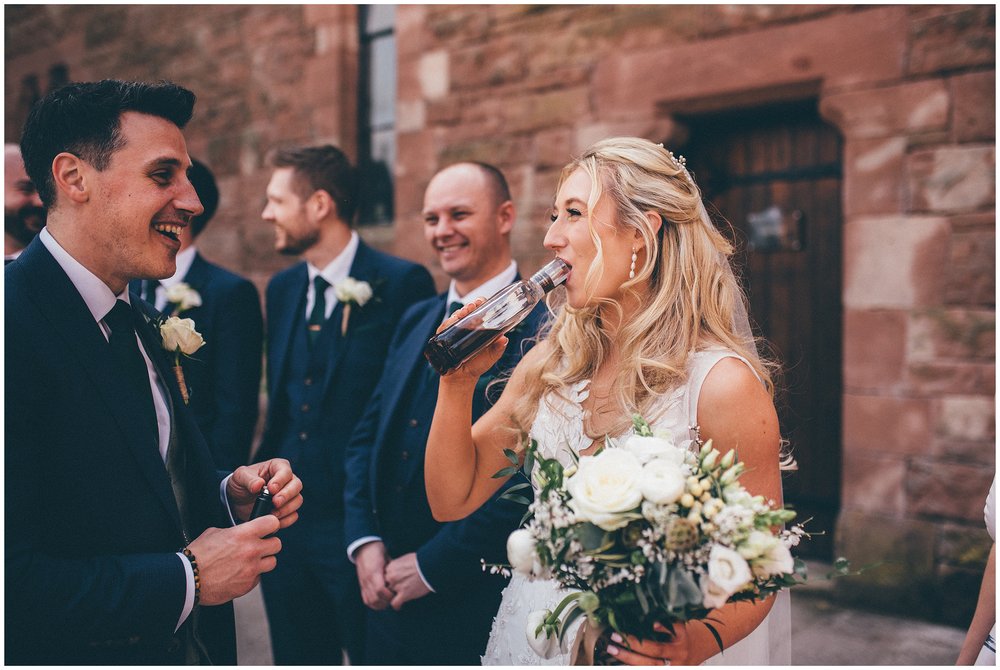 Bride drinks from a bottle of whisky at Peckforton Castle