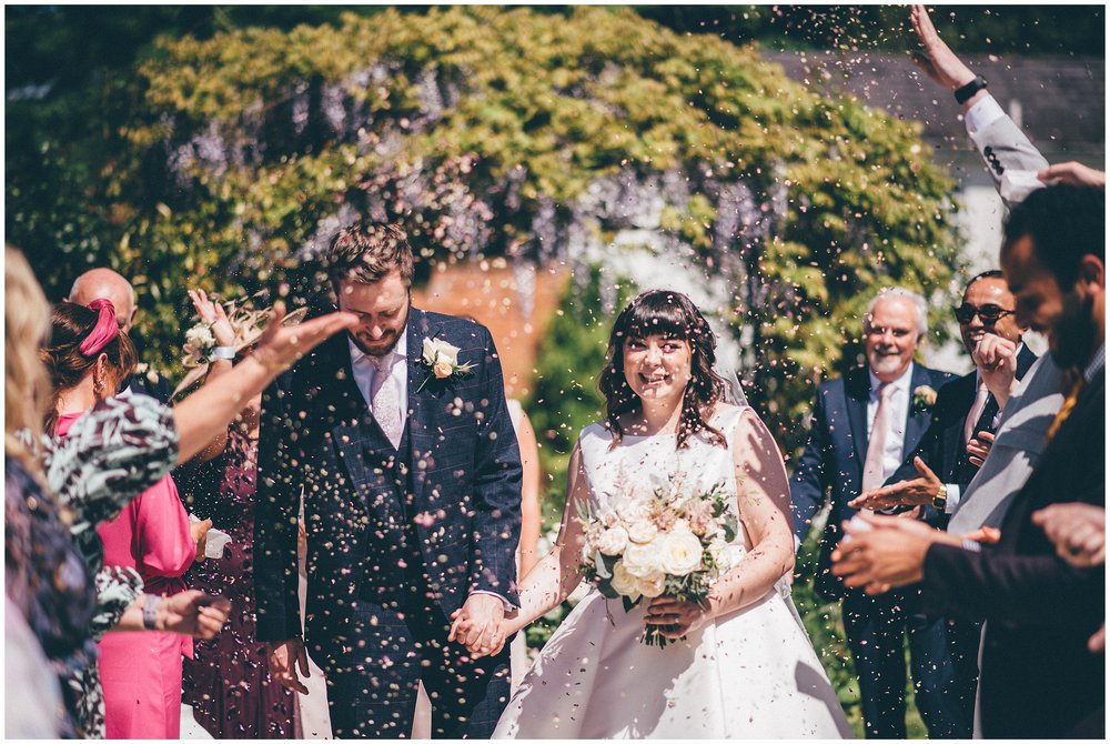 Guests throw confetti at the bride and groom at Rowton Hall