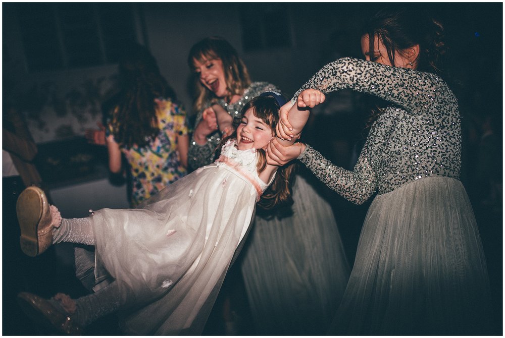 Bridesmaids swing the flower girl on the dance floor at Henham Barns wedding in Suffolk