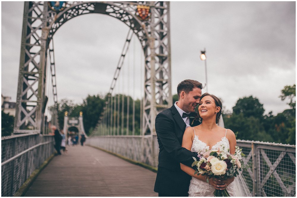 Bride and groom cuddle on the bridge at River Dee in Chester