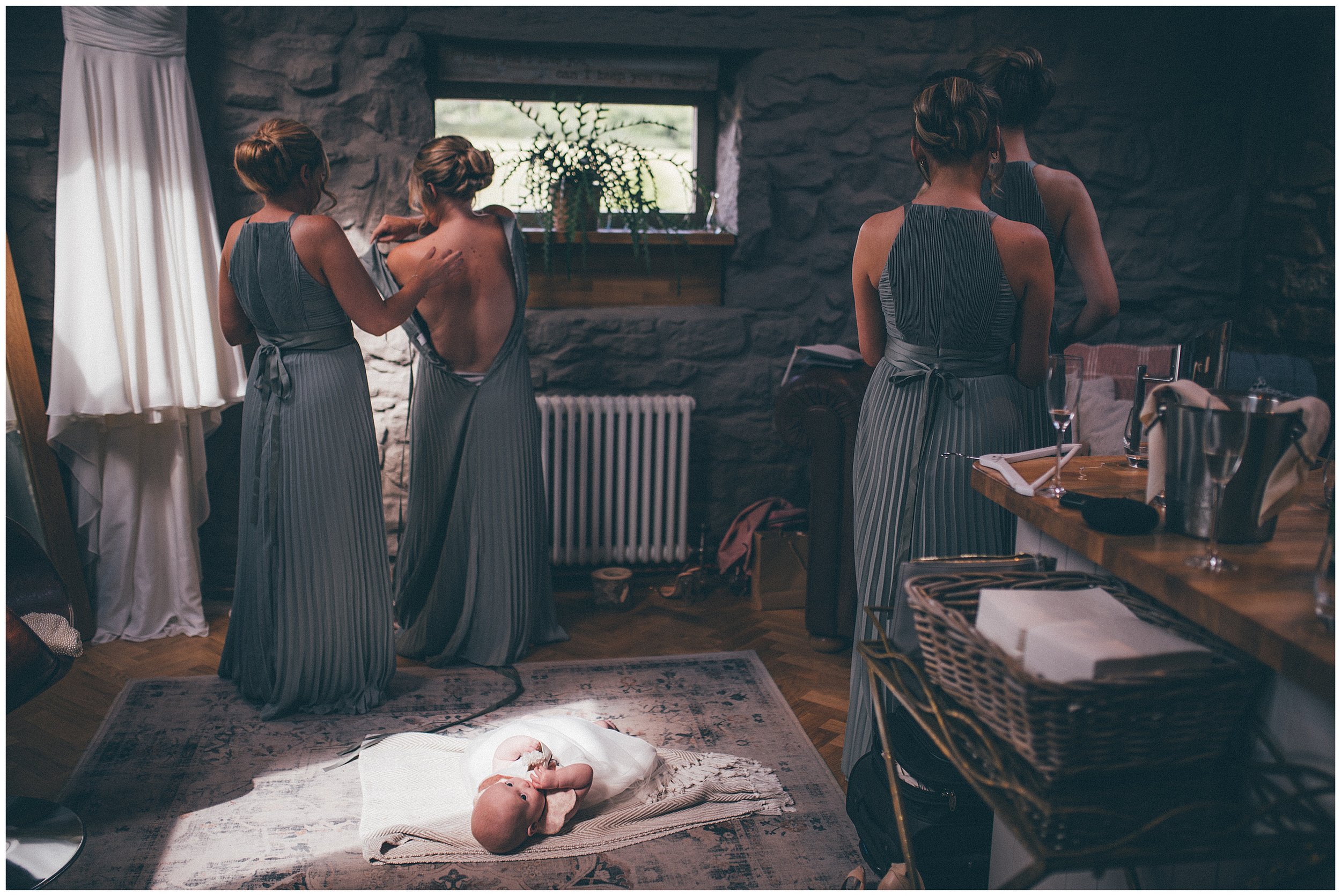 Bridesmaids get dressed whilst the baby flower girl babbles on the floor at Tower Hill Barns wedding